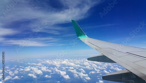 Wing of an airplane flying above the clouds. people looks at the sky from the window of the plane.