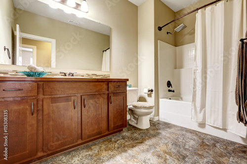 Classic American bathroom with brown cabinets and tile floor.