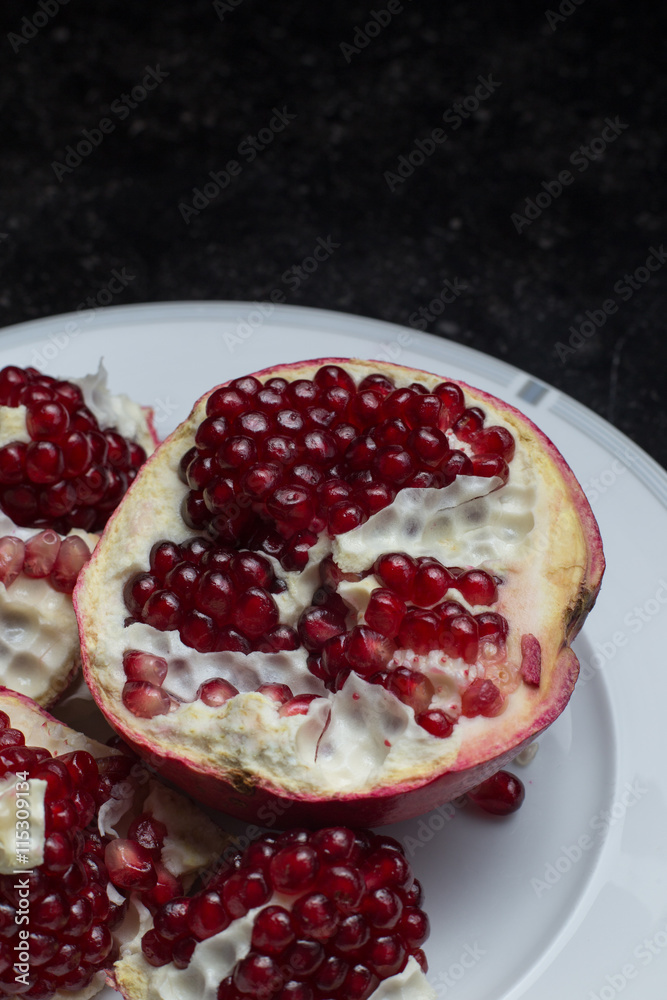 Red juicy pomegranate on dark marble background. Healthy, antioxidant, fresh, gourmet, delicious, organic fruit. Ingredient for grenadine. Close-up and copy space. Red juicy pomegranate on dark marble background. Healthy, antioxidant, fresh, gourmet, delicious, organic fruit. Ingredient for grenadine. Close-up and copy space.