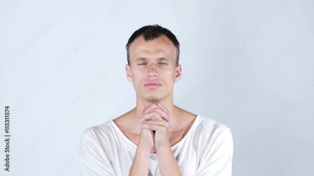 Closeup portrait young man praying hands hoping for best asking for forgiveness Closeup portrait young man praying hands hoping for best asking for forgiveness