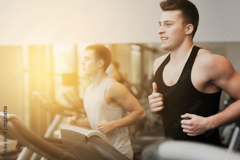 smiling men exercising on treadmill in gym smiling men exercising on treadmill in gym