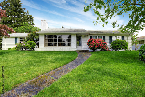 Foto American white rambler with green grass and flower bed.
