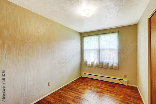 Small empty basement room with hardwood floor and beige walls