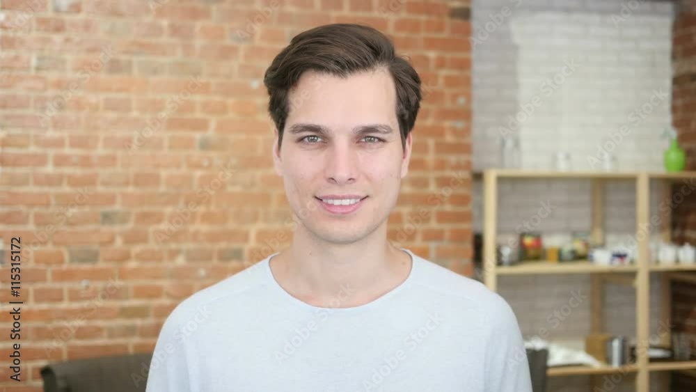 Portrait of confident young man smiling and standing in his office Portrait of confident young man smiling and standing in his office
