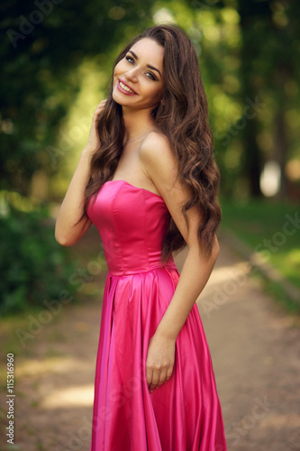 Beauty romantic girl outdoor. Pretty young model dressed in long evening dress posing outdoors at path in the park. Full body Portrait with beautiful bokeh