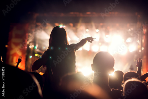 Girl on shoulders in the crowd at a music festival. Blurred movement.