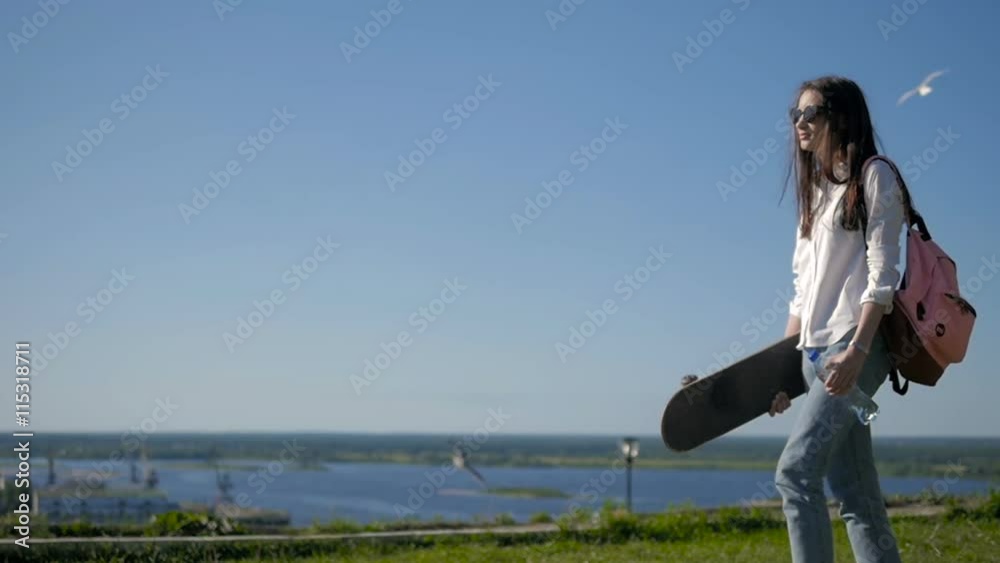 Side View of Young Beautiful Girl Walking at Park Holding a Skateboard Side View of Young Beautiful Girl Walking at Park Holding a Skateboard