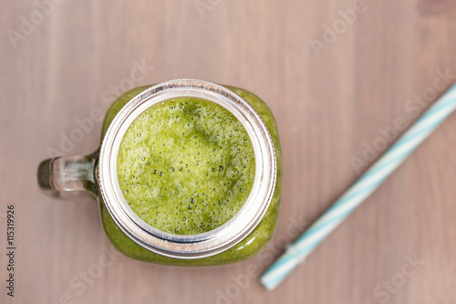 A green smoothie in a mason jar on wooden background