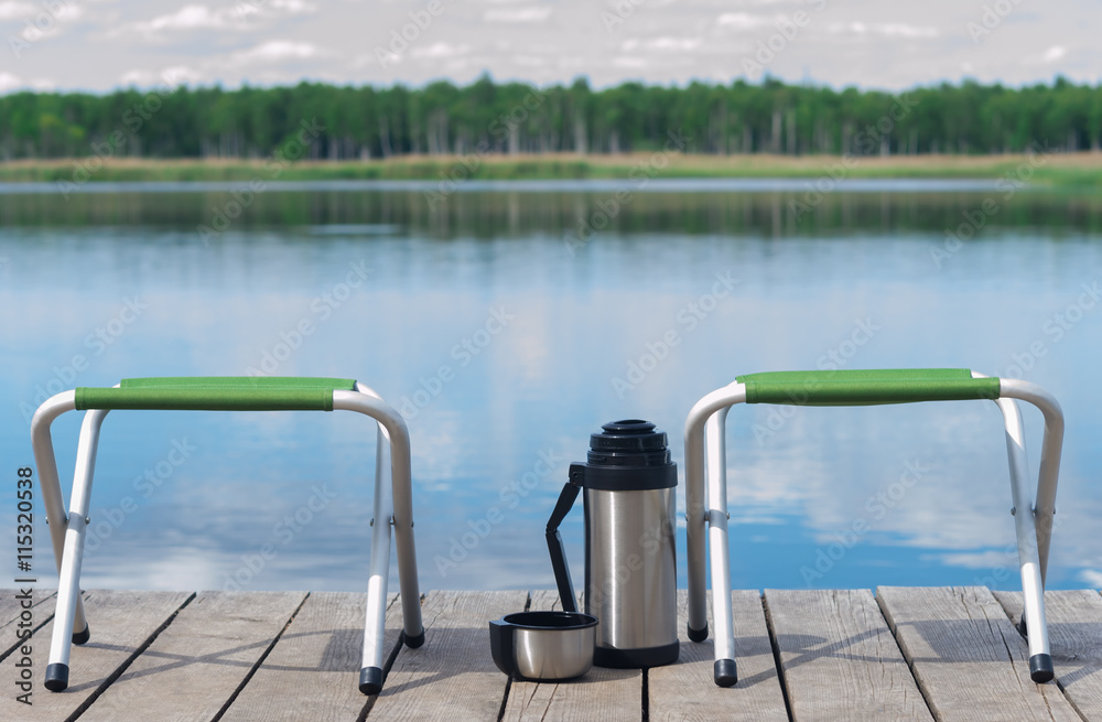 Obraz premium two vacant seats on the pier and hot tea waiting for guests