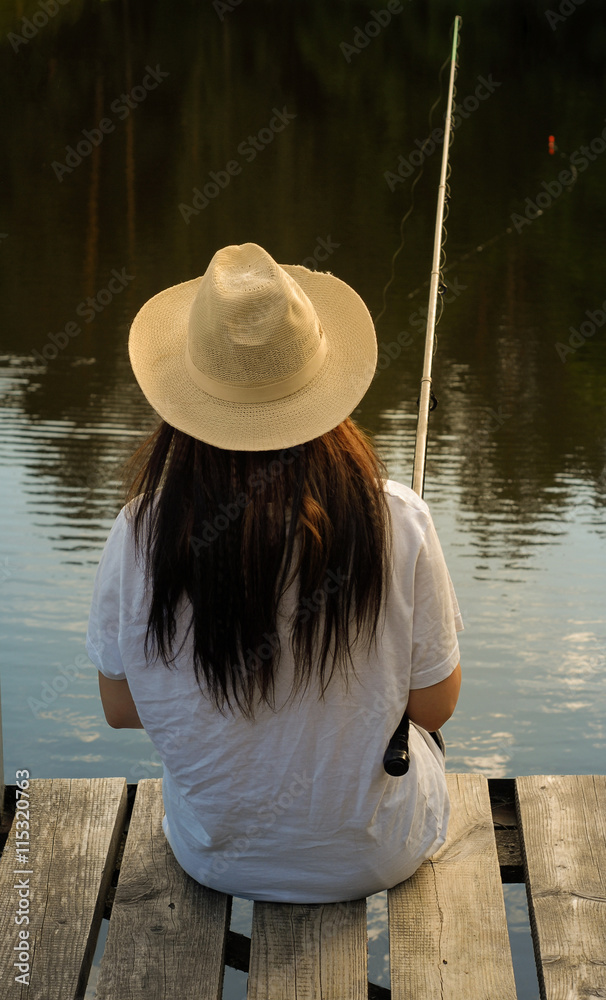 Young woman fishing in pond in summer evening