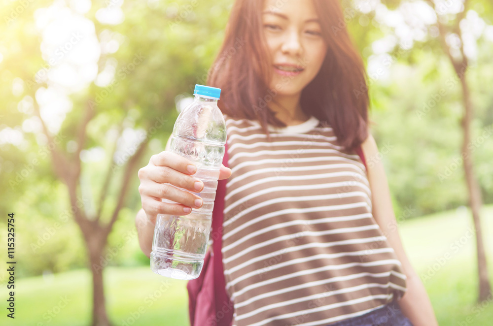Close up female hand holding water while smiling at summer green park outdoor and bokeh nature background, healthy concept. Close up female hand holding water while smiling at summer green park outdoor and bokeh nature background, healthy concept.