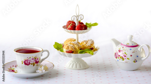 Cream puff cakes or profiterole filled with whipped cream served with strawberries in plateau