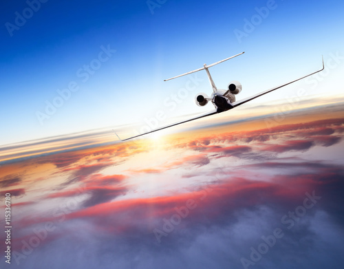 Private jet plane flying above clouds