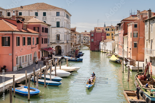 Female crew is training on a rowing boat in venice canal. photo