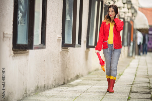 Canvas Print Smiling young woman is walking in a city on a rainy day