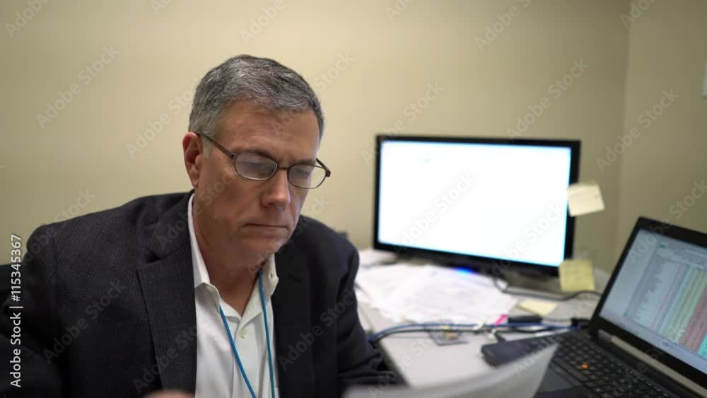 Mature executive going over paperwork in his cluttered office. Mature executive going over paperwork in his cluttered office.