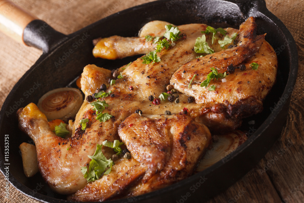 Chicken tobacco with herbs and garlic in a pan close-up. horizontal
Chicken tobacco with herbs and garlic in a pan close-up. horizontal
