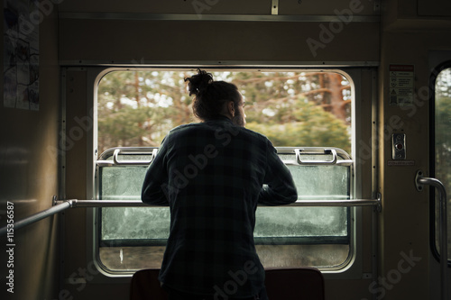 Rear view of a man looking out through window while travelling in train photo