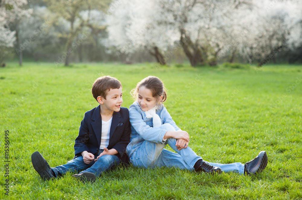 boy and girl sitting on green meadow boy and girl sitting on green meadow