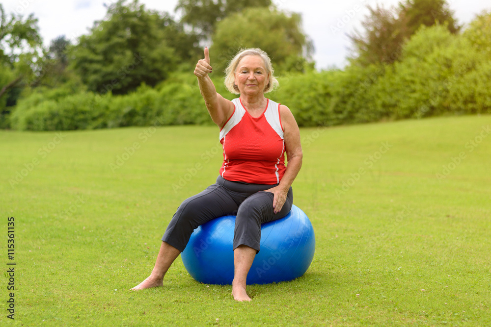 Woman seated on stability ball with thumb up