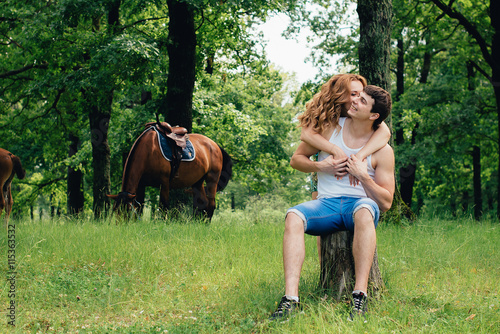 Lovers kissing and hugging on the background of horses