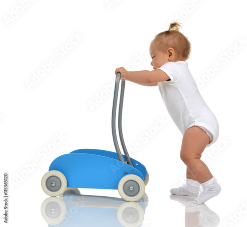Fototapeta Smiling baby girl toddler with toy walker make first steps