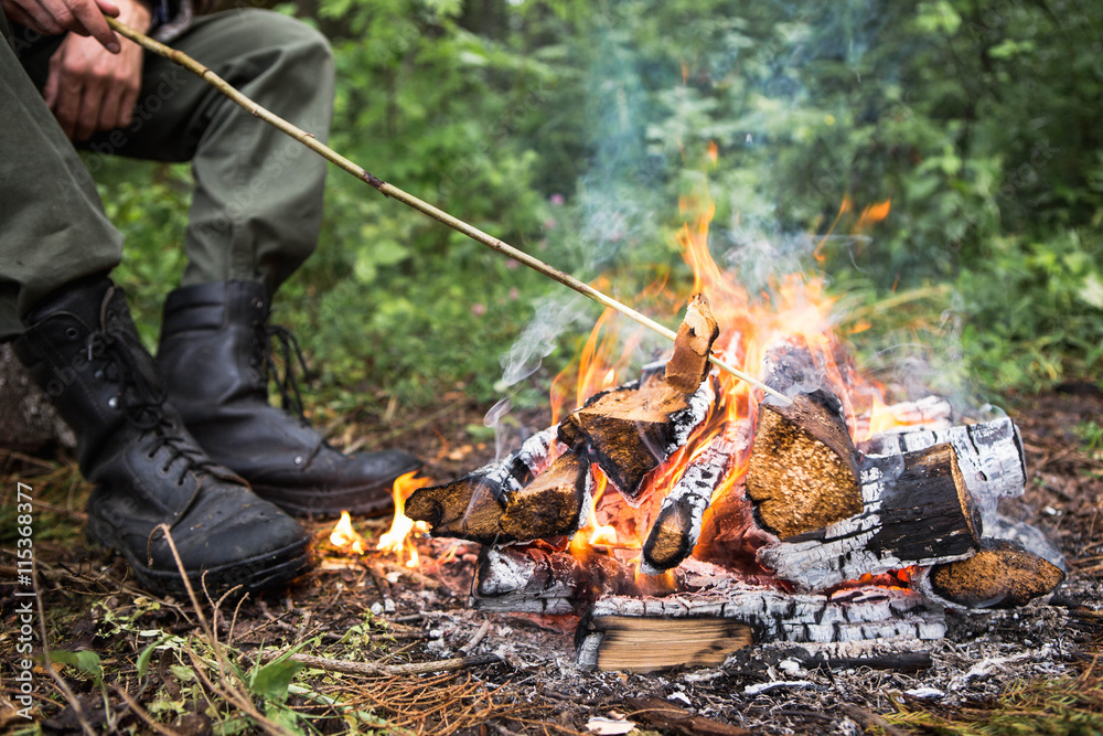 A man warms himself by the fire in the forest, rain, autumn A man warms himself by the fire in the forest, rain, autumn