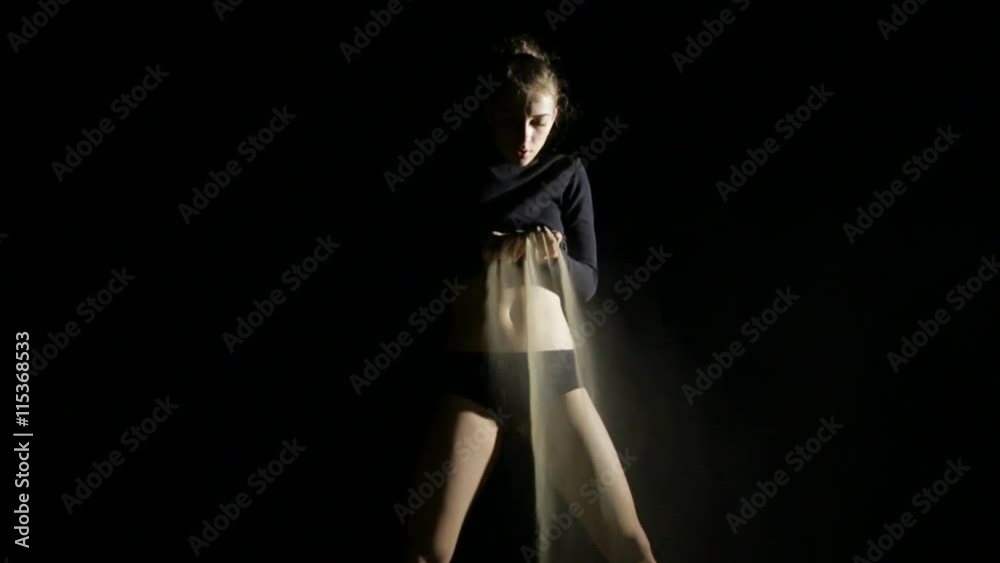 Charmed young woman pouring sand at night beach, black background Charmed young woman pouring sand at night beach, black background
