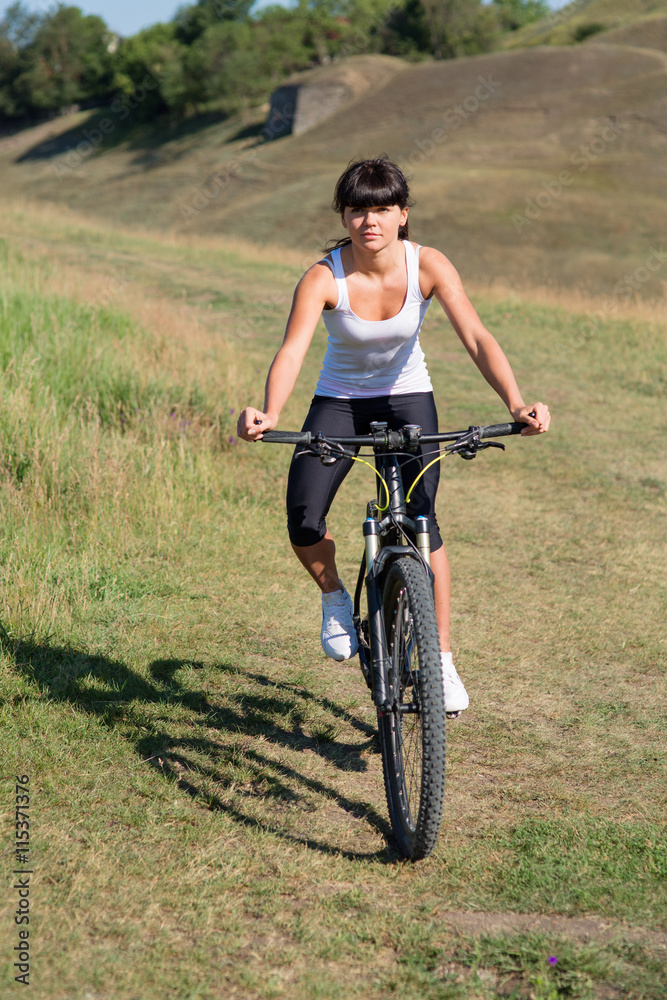 Young lady with bicycle on a spring meadow