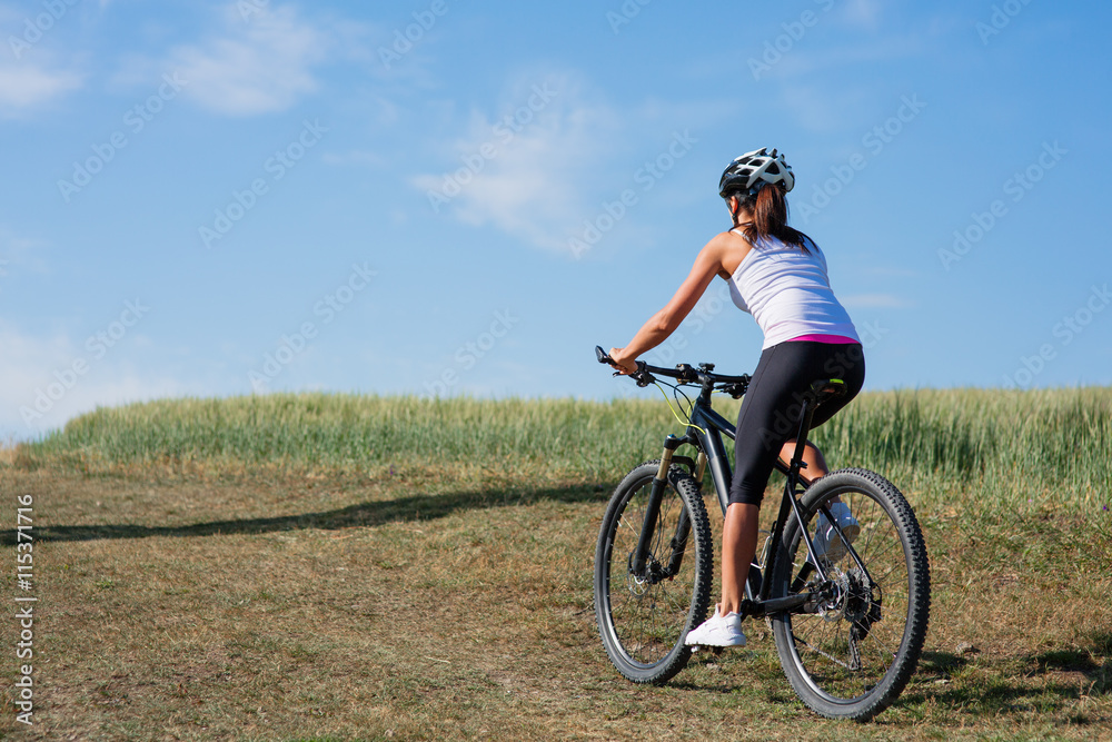 Young lady with bicycle on a spring meadow