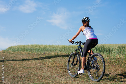 Young lady with bicycle on a spring meadow © Aleksey