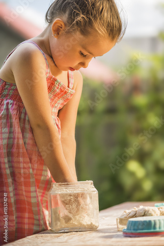 Happy little chef girl smeary with flour baking and having fun playing with flour outdoor © alexandrum01