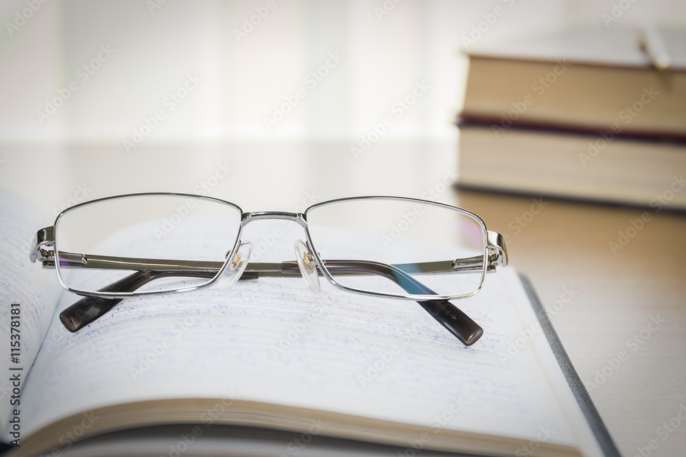 Eyeglasses put on notebook on wood table Eyeglasses put on notebook on wood table