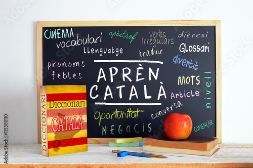 Blackboard in a classroom with the message LEARN CATALAN and some text