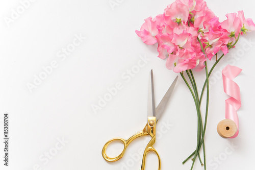 scissors, flowers and ribbon on white table photo