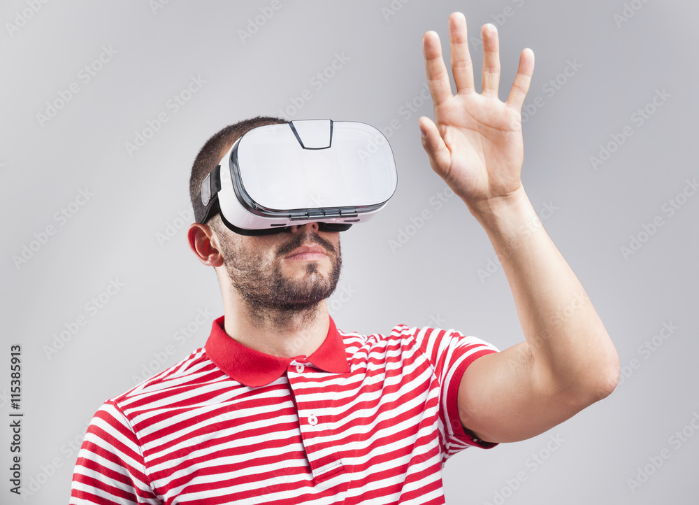 Young guy using a VR headset on gray background Young guy using a VR headset on gray background