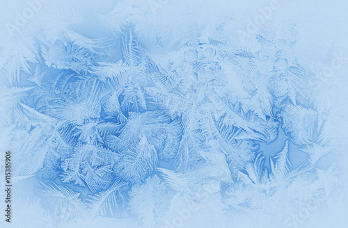 Bright blue frost pattern on a window glass in the winter (as an abstract winter background), retro style