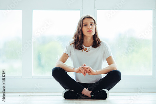 Free Download Lost in thoughts. Young beautiful brunette hipster woman sitting on floor near huge window and looking away - GFXLoad