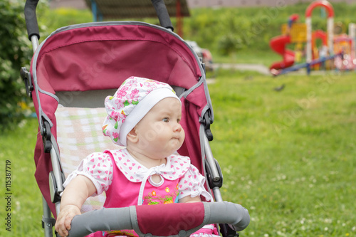 little newborn girl sitting in a baby carriage © siaphoto