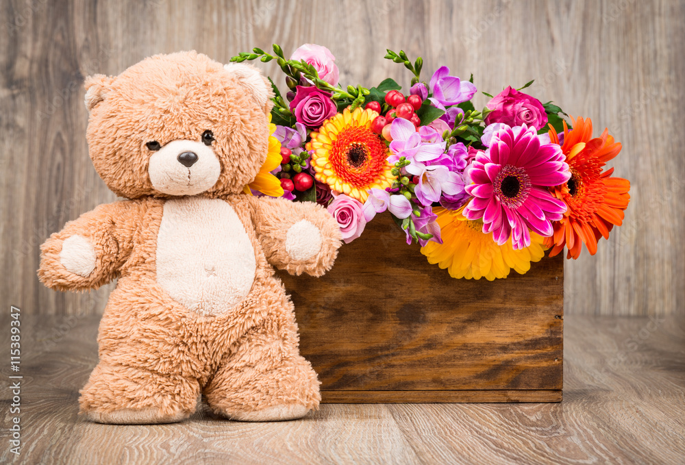 Obraz premium Beautiful flowers and a teddy bear on wooden background