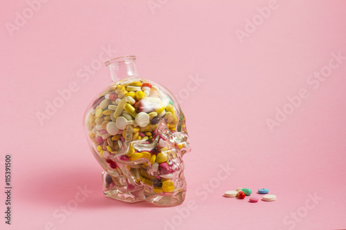 Kill pill / Creative medicine and health care concept photo of a skull glass filled with drugs and pills on pink background.