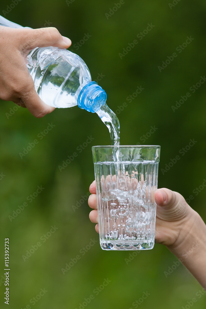 hand pouring water from bottle into glass hand pouring water from bottle into glass