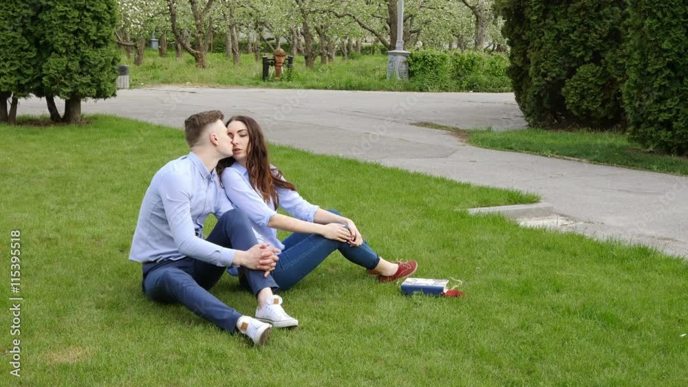 Young couple kissing sitting on green grass outdoor
Young couple kissing sitting on green grass outdoor