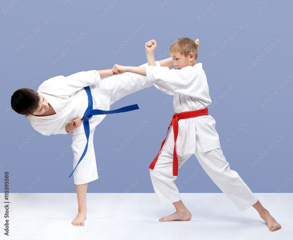 On a light background boys are beating punch arm and kick leg On a light background boys are beating punch arm and kick leg