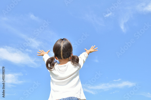 青空でバンザイする女の子（後姿）