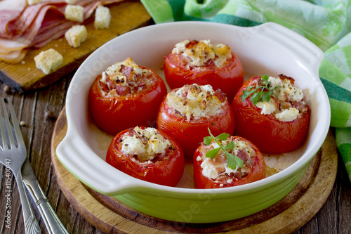 Baked stuffed tomatoes with bacon and feta cheese on a wooden ta