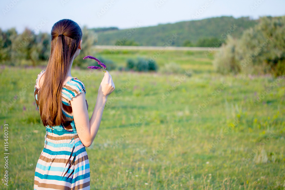 Woman on summer meadow with flowers at sunset Woman on summer meadow with flowers at sunset