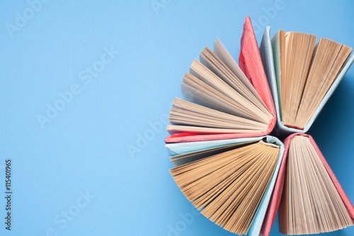 Top view of bright colorful hardback books in a circle. Open book, fanned pages.   Education essential for self improvement, gaining knowledge and success in our careers, business and personal lives.