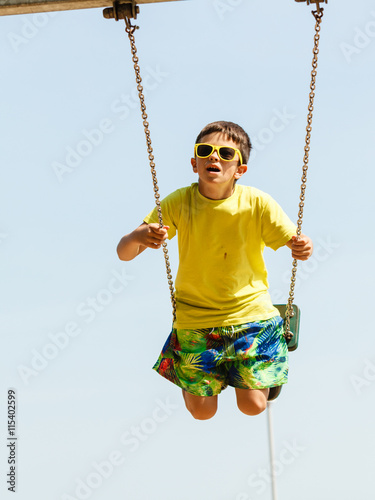 Boy playing swinging by swing-set.