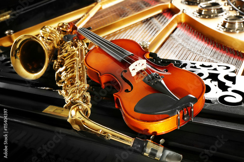 Violin and saxophone lying on piano, close up